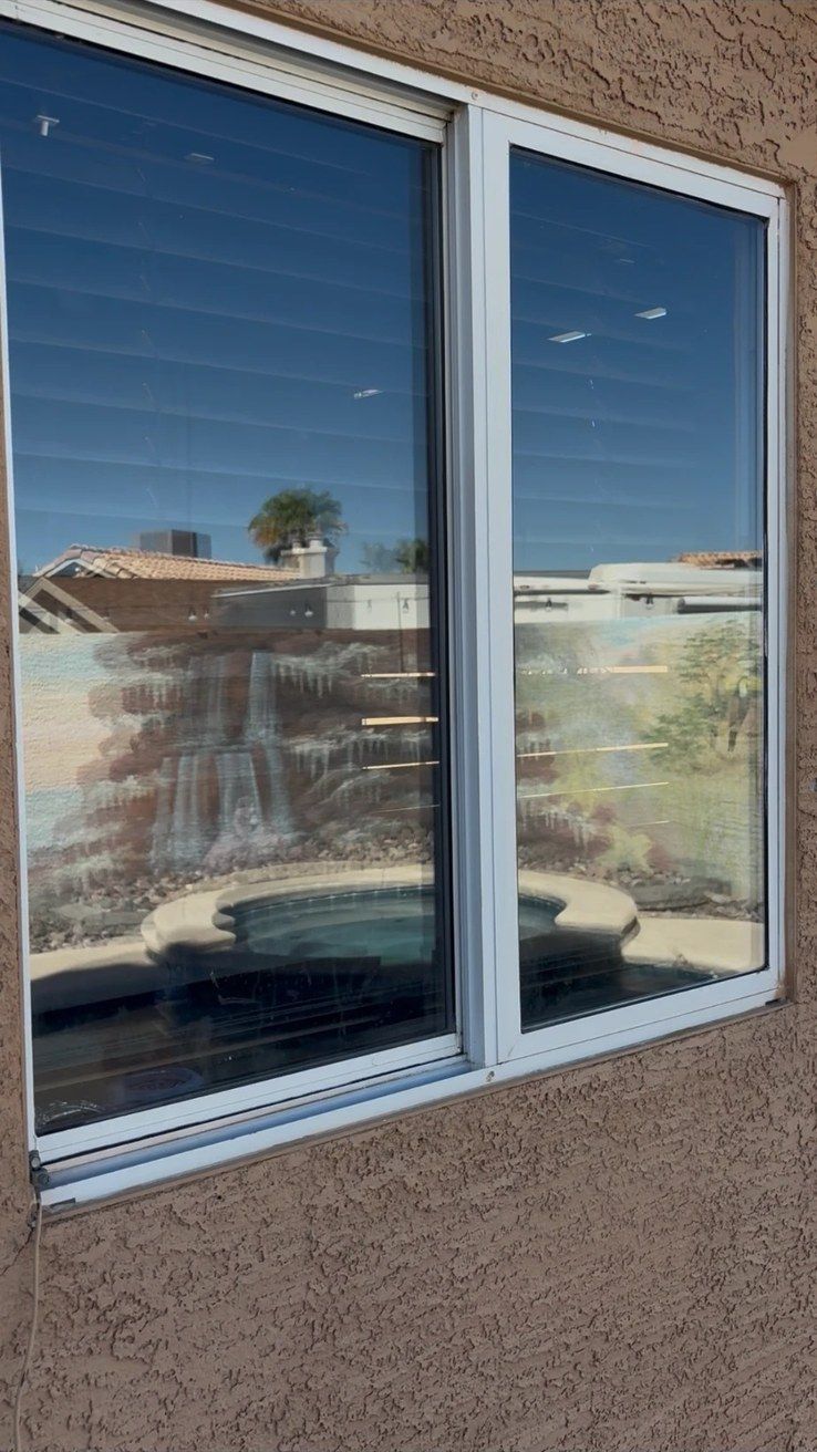 Cleaned white-framed window at a Las Vegas Valley home, with the pool and yard mirrored in the glass